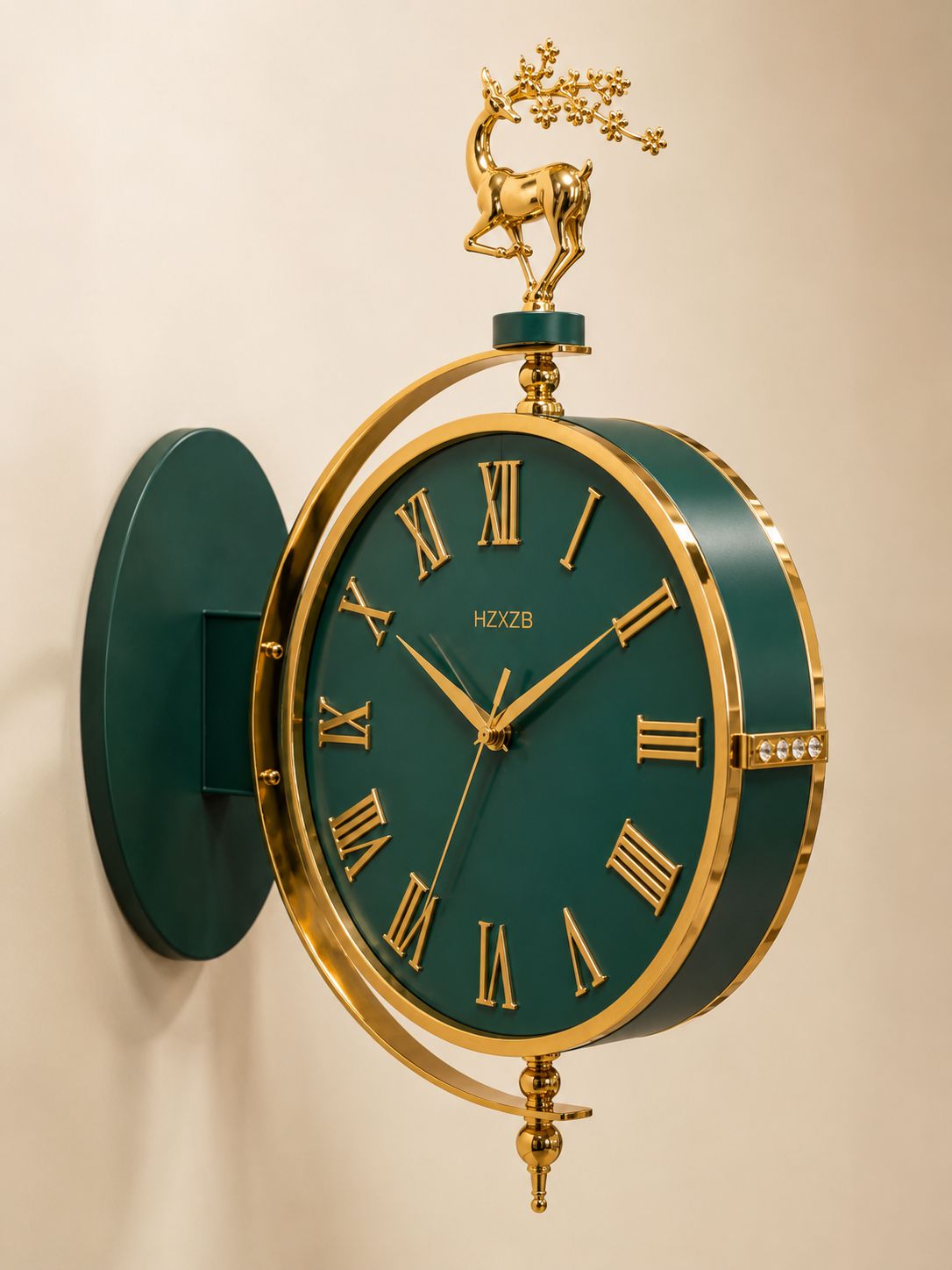 A decorative wall clock with a dark green face and matching green wall mount, framed in gold-tone metal. The clock features gold Roman numerals, ornate gold hands, a gold decorative branch with a deer topper, and curved gold support bars.