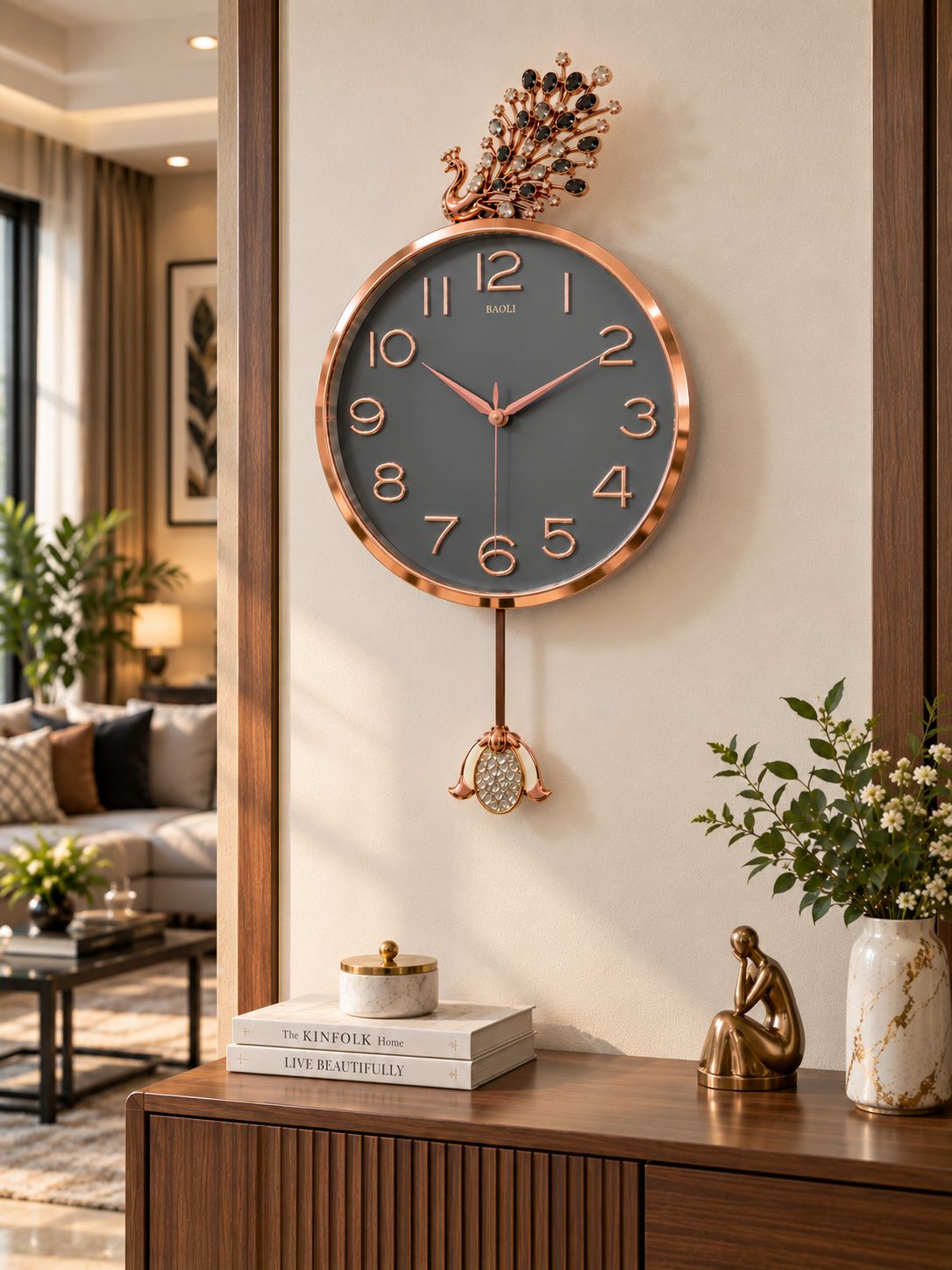 A round wall clock with a rose gold metallic frame and a dark gray clock face, hanging on a beige wall in a modern living room setting above a wooden console table.