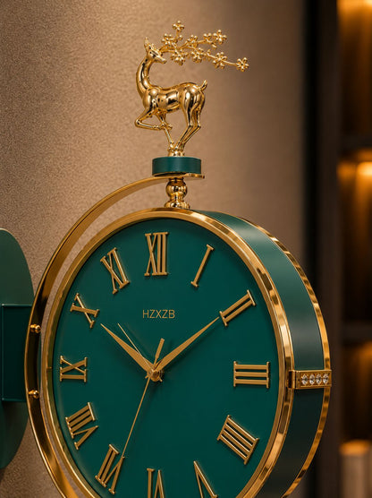 A close-up of an ornate wall clock with a dark teal-green face and gold-tone Roman numerals, surrounded by a gold-tone frame. The top is decorated with a gold deer figurine holding a flowering branch.