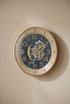 Decorative wall clock with intricate design on a beige wall
