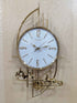 A decorative gold wall clock featuring a reindeer and mountain design, with a white clock face and gold hands.