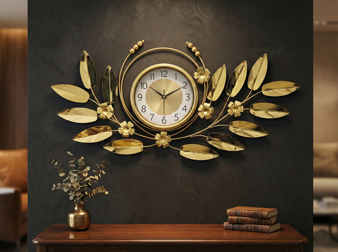 Large gold metal wall clock with leaf design on grey wall for living room decor.