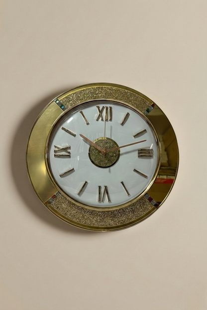 Round wall clock with gold frame and Roman numeral markers on a beige wall.