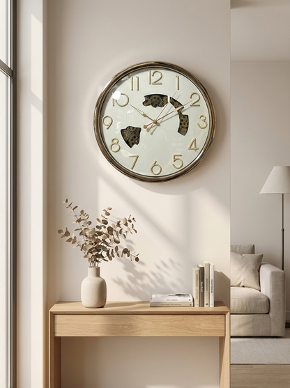Wall clock on a wall in a living room with a table and books.